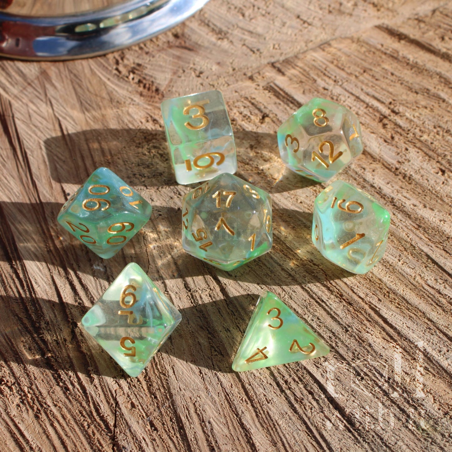 Set of green clear cute elf elven dice with gold numbers on a wooden surface