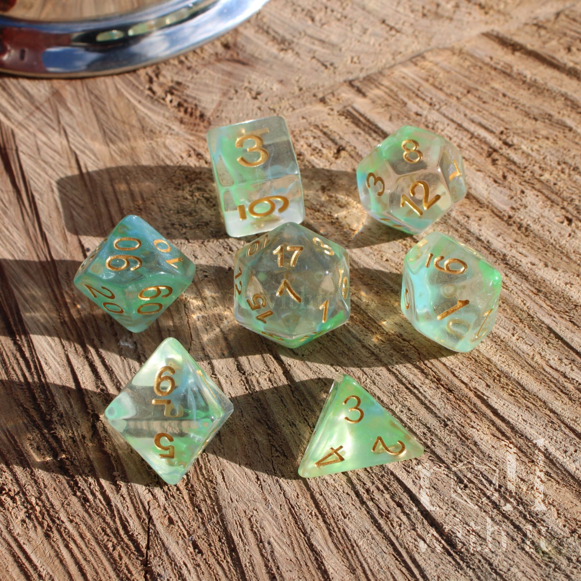 Set of green clear cute elf elven dice with gold numbers on a wooden surface