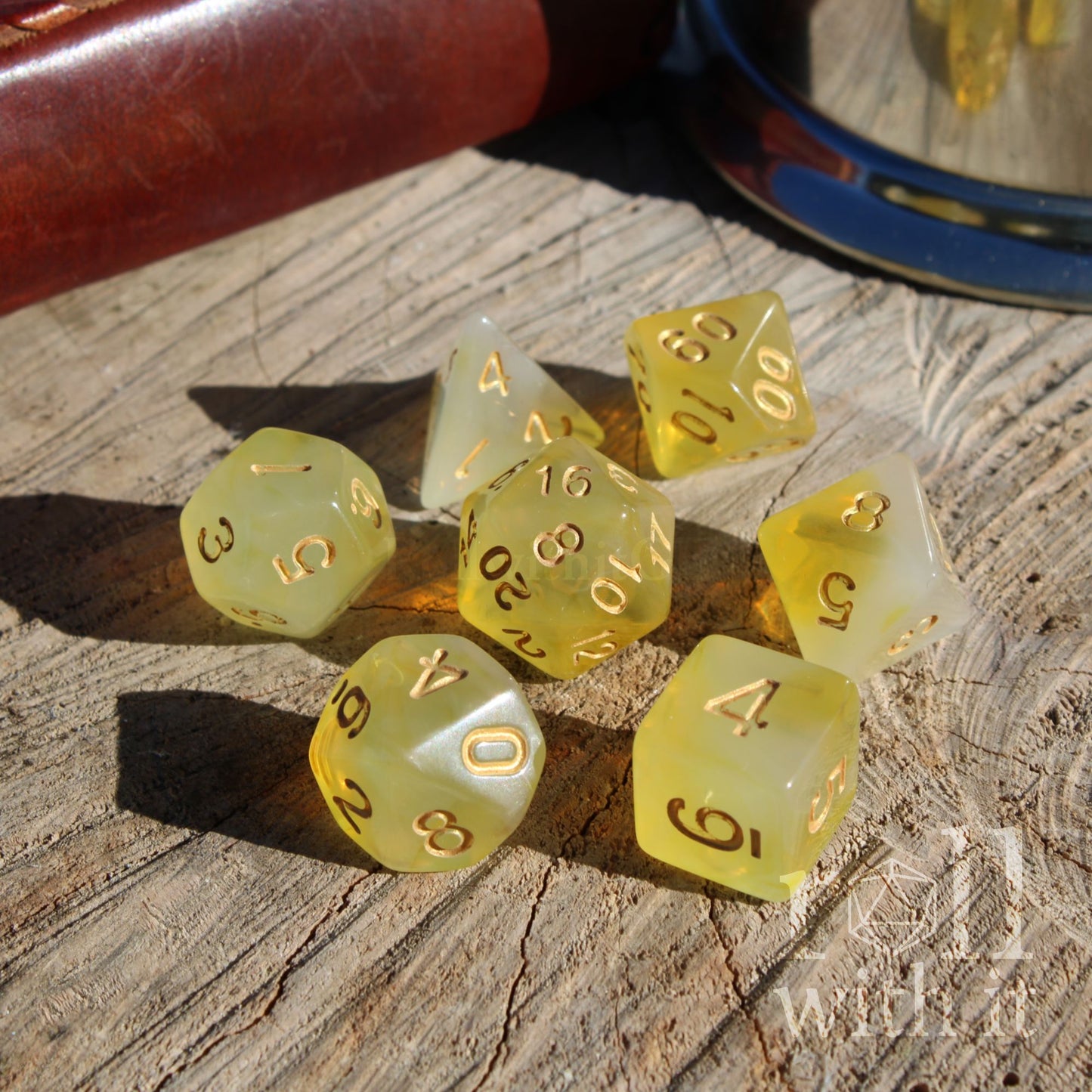 Set of 7 yellow polyhedral dice with gold numbers on a wooden surface