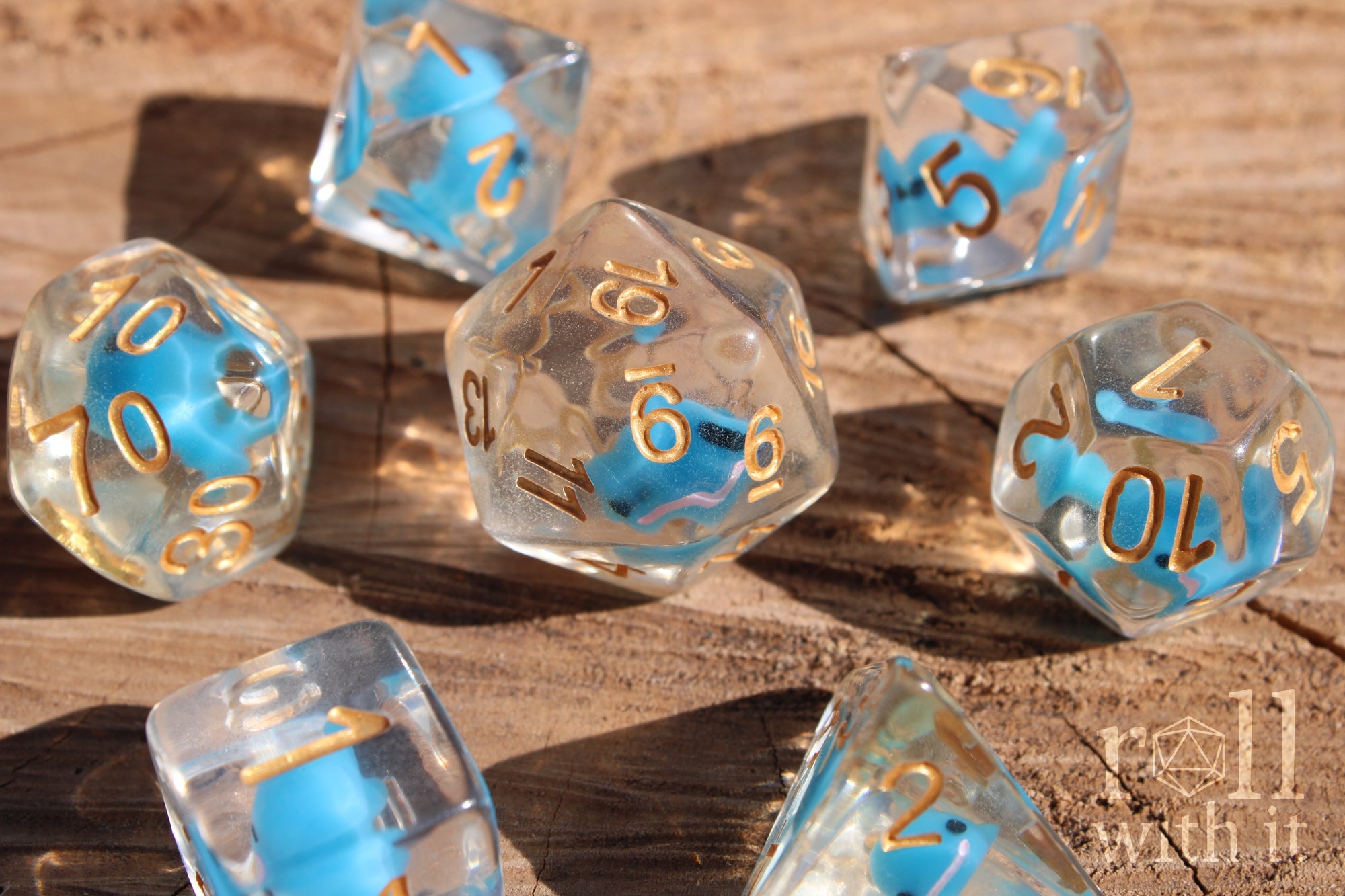 Set of clear polyhedral DnD dice with a small blue whale inside on a wooden surface