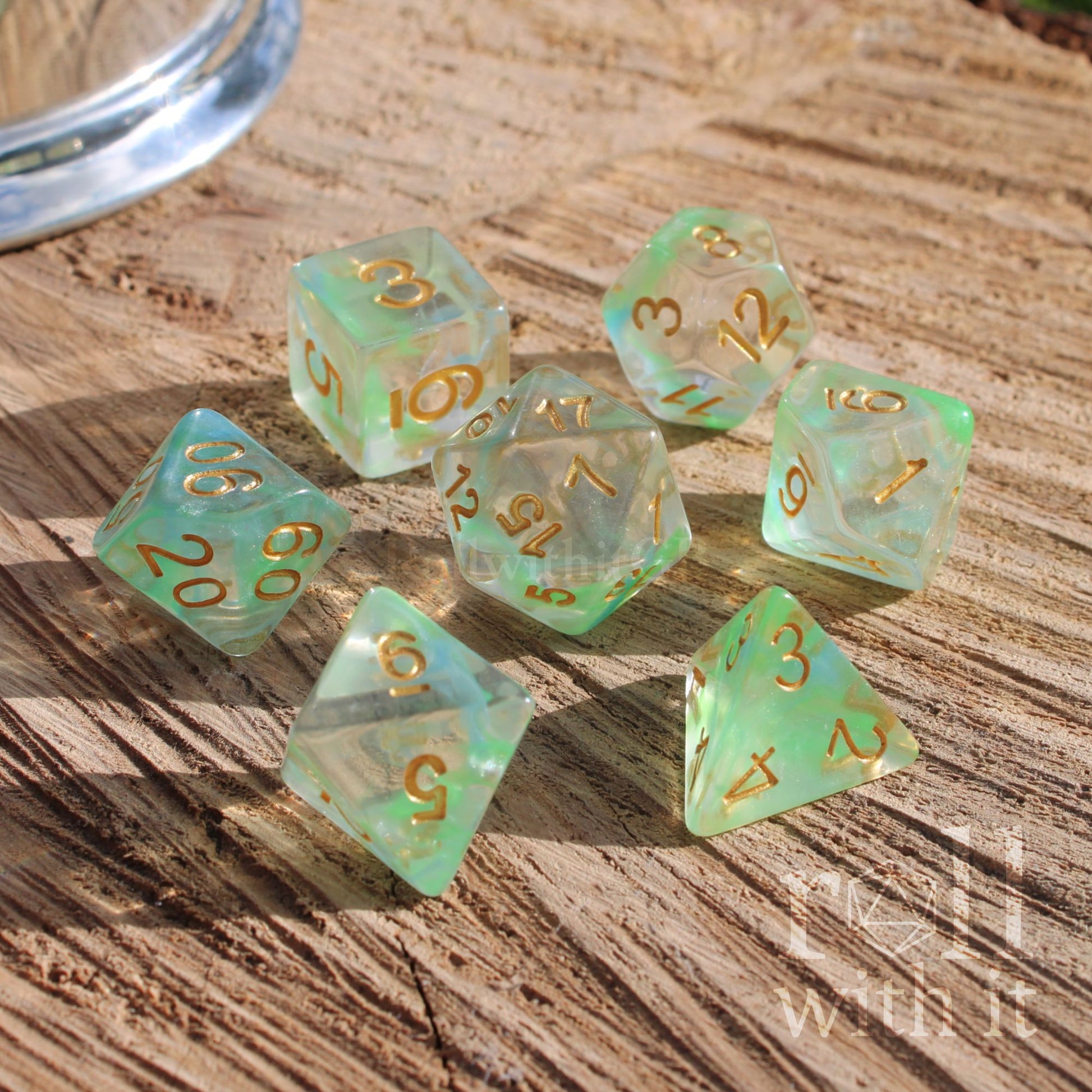Set of 7 polyhedral TTRPG gaming green dice with gold numbers on a wooden surface