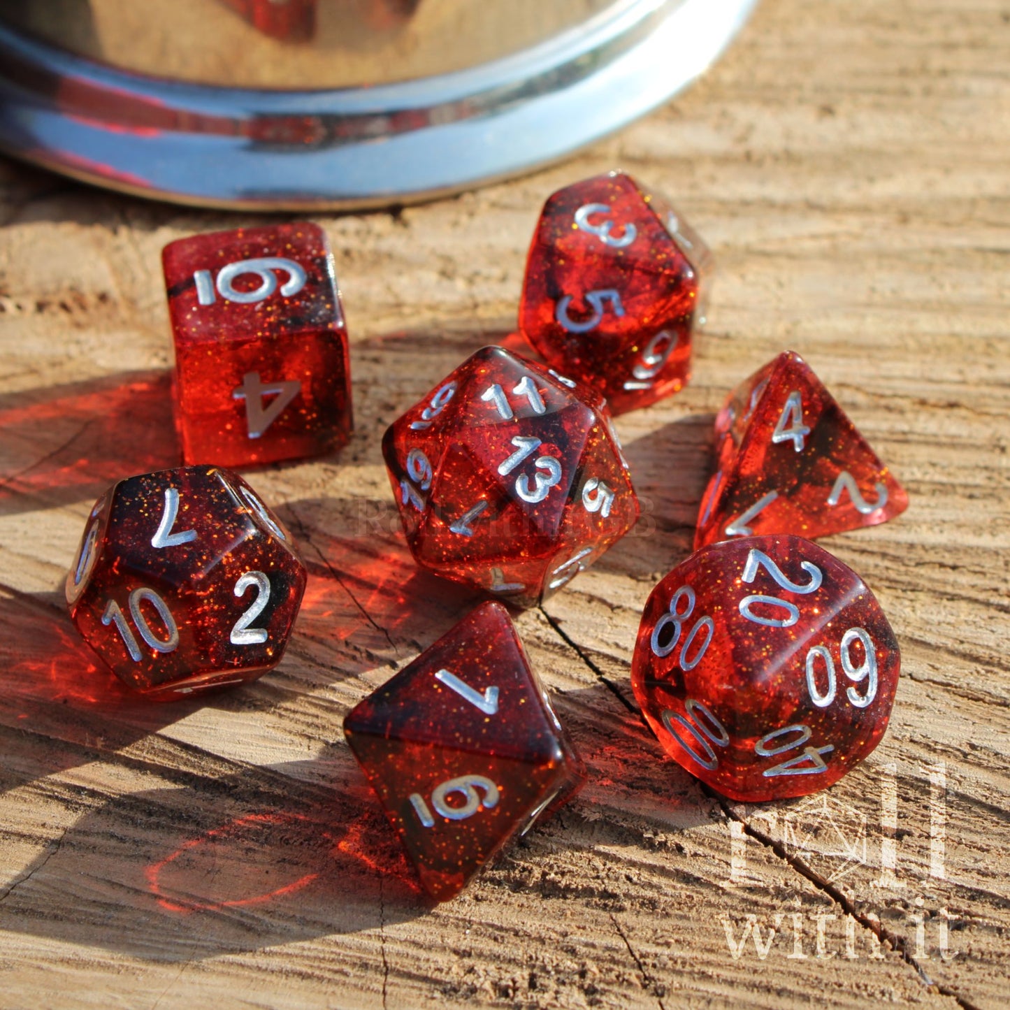 Angled photo view of crimson red D&D dice set with silver numbers on a wooden surface