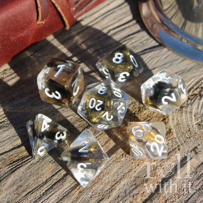Set of clear golden glitter black dice with black numbers on a wooden surface