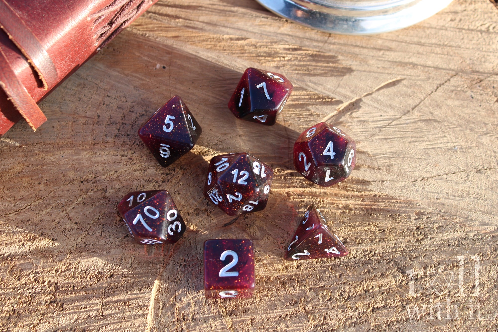Set of glittery deep red and purple polyhedral roleplaying dice with numbers on a wooden surface