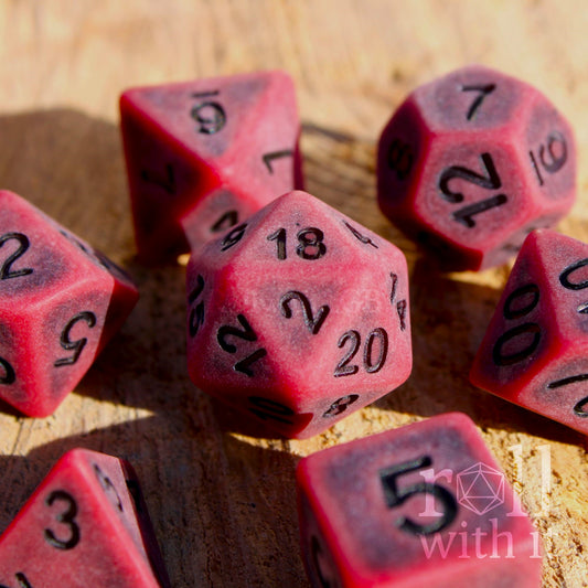 Matte worn maroon red dice set with black lettering on a wooden surface