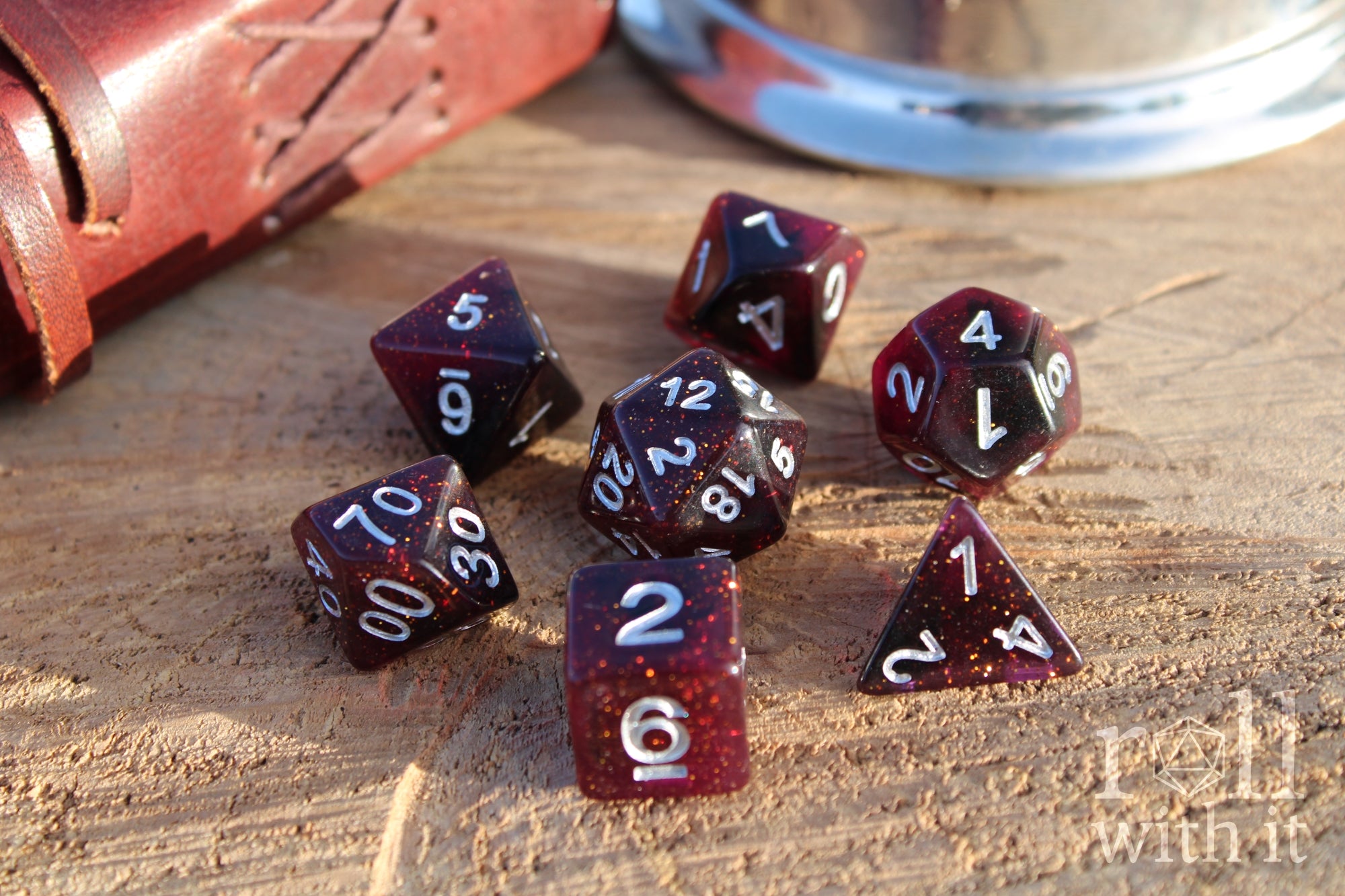 Set of glittery deep red and purple polyhedral roleplaying dice with numbers on a wooden surface