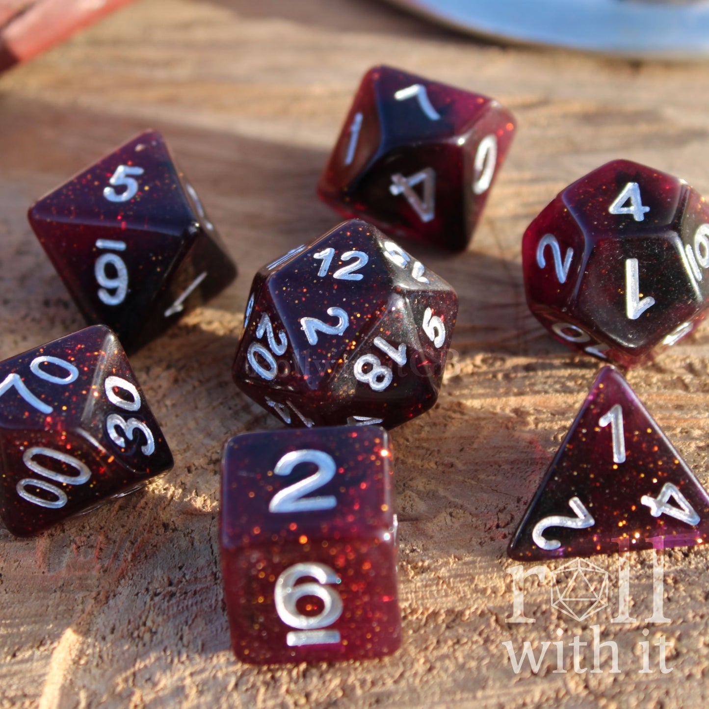Set of glittery deep red and purple polyhedral roleplaying dice with numbers on a wooden surface