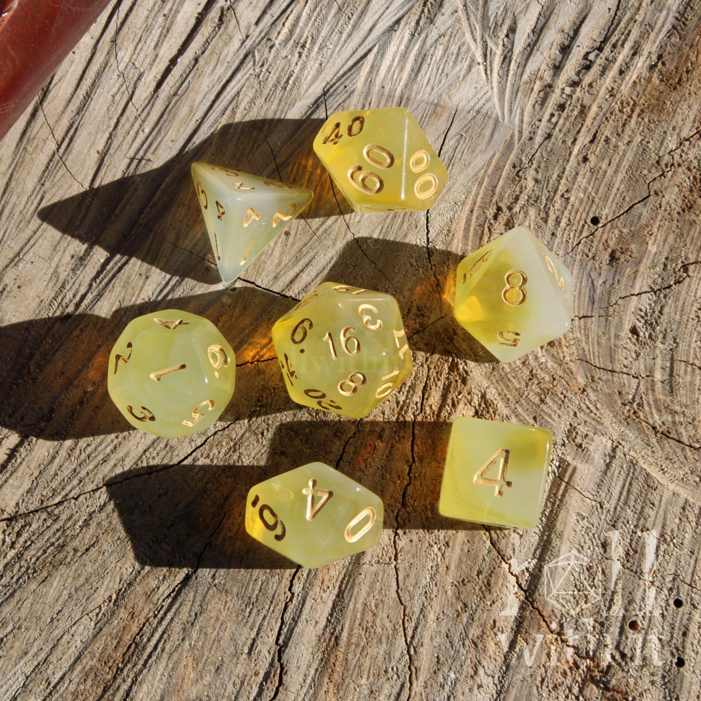 Set of 7 yellow polyhedral tabletop roleplaying gamer dice on a wooden surface