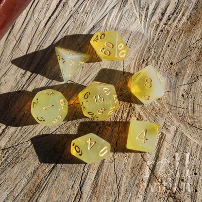 Set of 7 yellow polyhedral tabletop roleplaying gamer dice on a wooden surface
