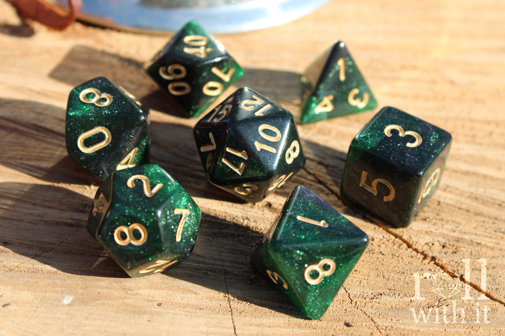Set of starry green glittery polyhedral dice with gold numbers on a wooden surface