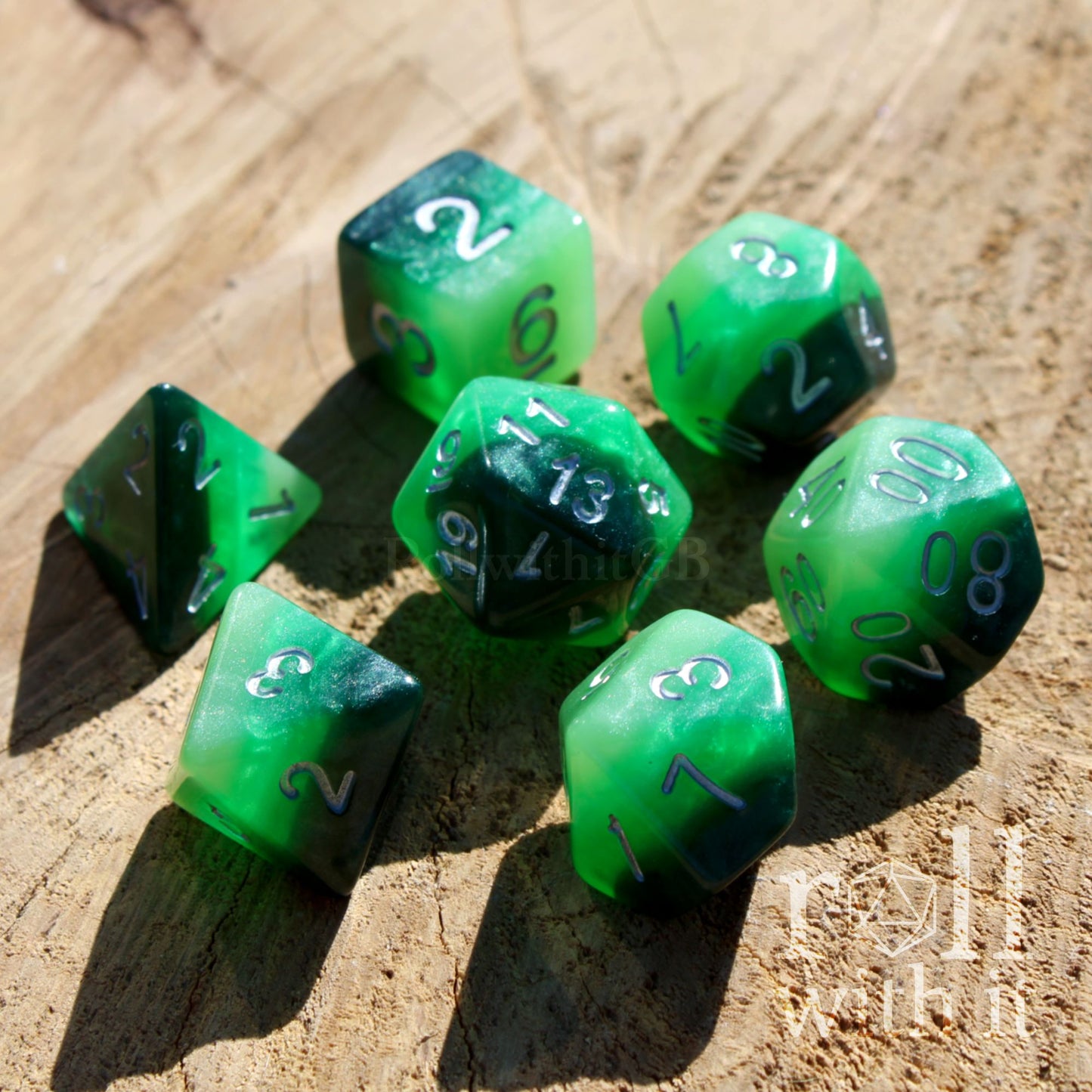 Bright set of 7 green polyhedral fantasy roleplaying TTRPG dice set on a wooden surface with 'roll with it' branding.