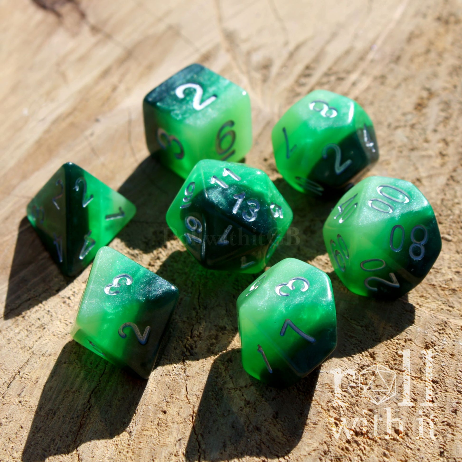 Bright set of 7 green polyhedral fantasy roleplaying TTRPG dice set on a wooden surface with 'roll with it' branding.