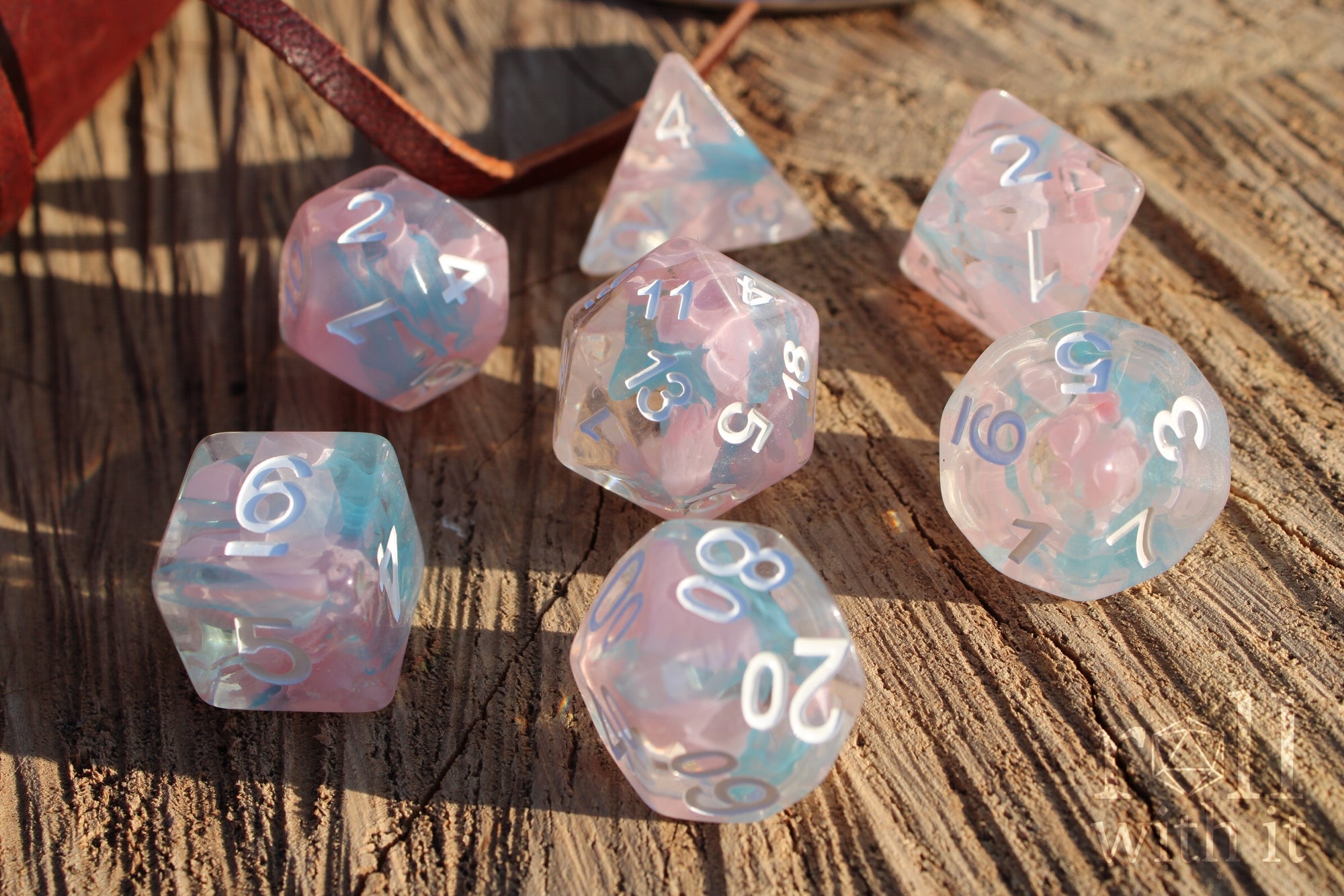 Set of pink and pale blue translucent polyhedral roleplaying dice on a wooden surface