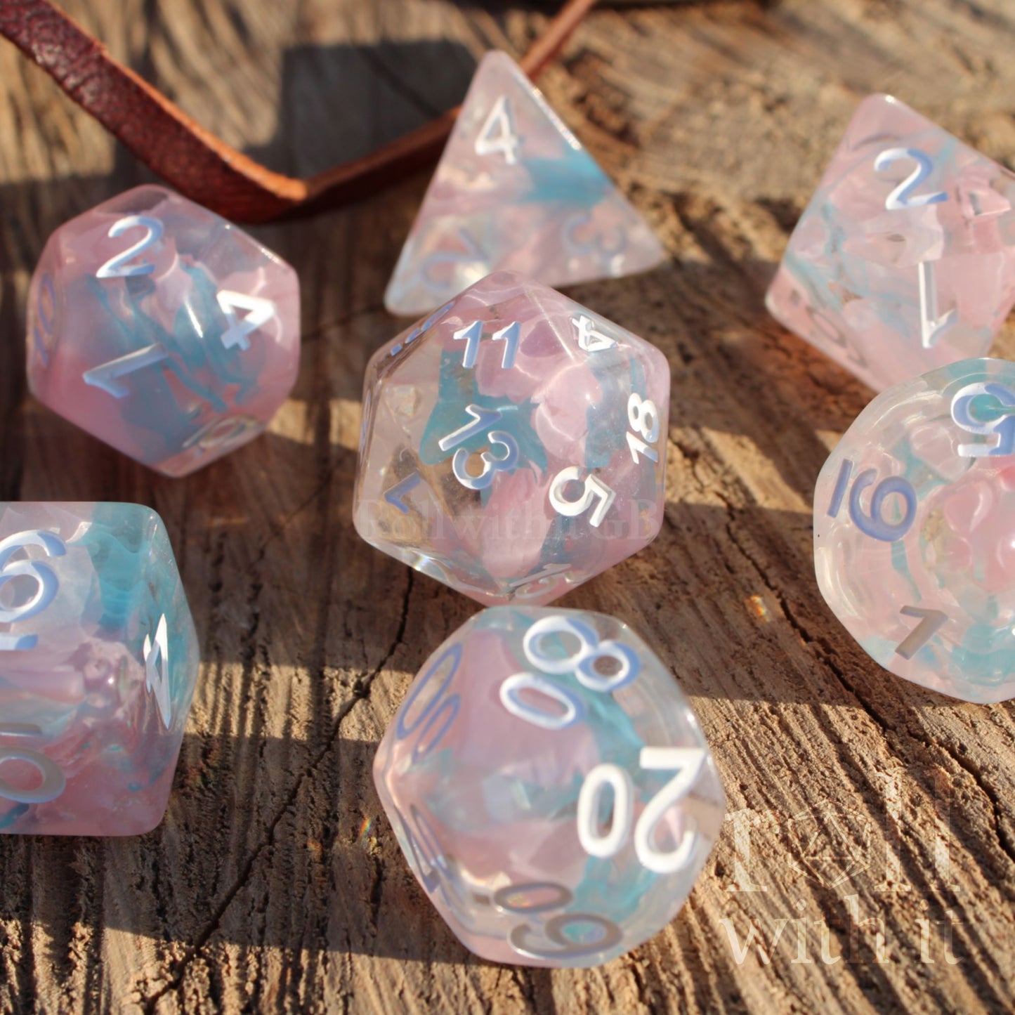 Set of pink and pale blue translucent polyhedral roleplaying dice on a wooden surface