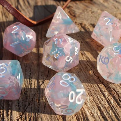 Set of pink and pale blue translucent polyhedral roleplaying dice on a wooden surface