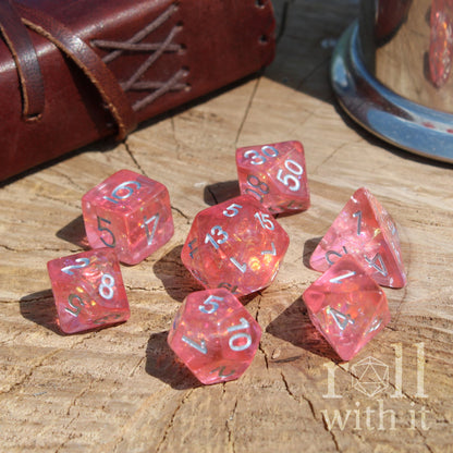 Pink reflective bright girly polyhedral dice set on a wooden surface with 'roll with it' branding.