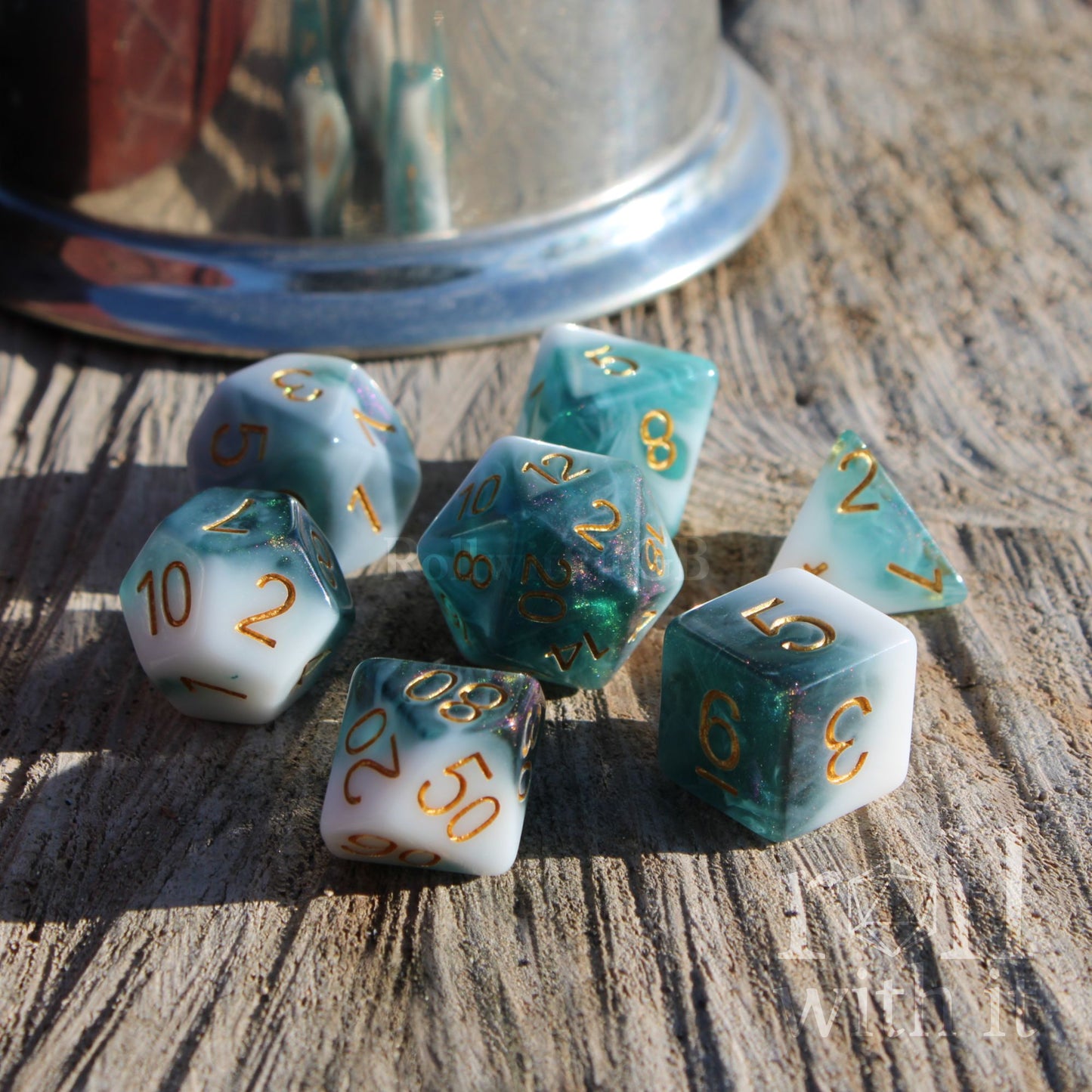Set of shiny glitter filled glacier blue and white dice with gold numbers on a wooden surface