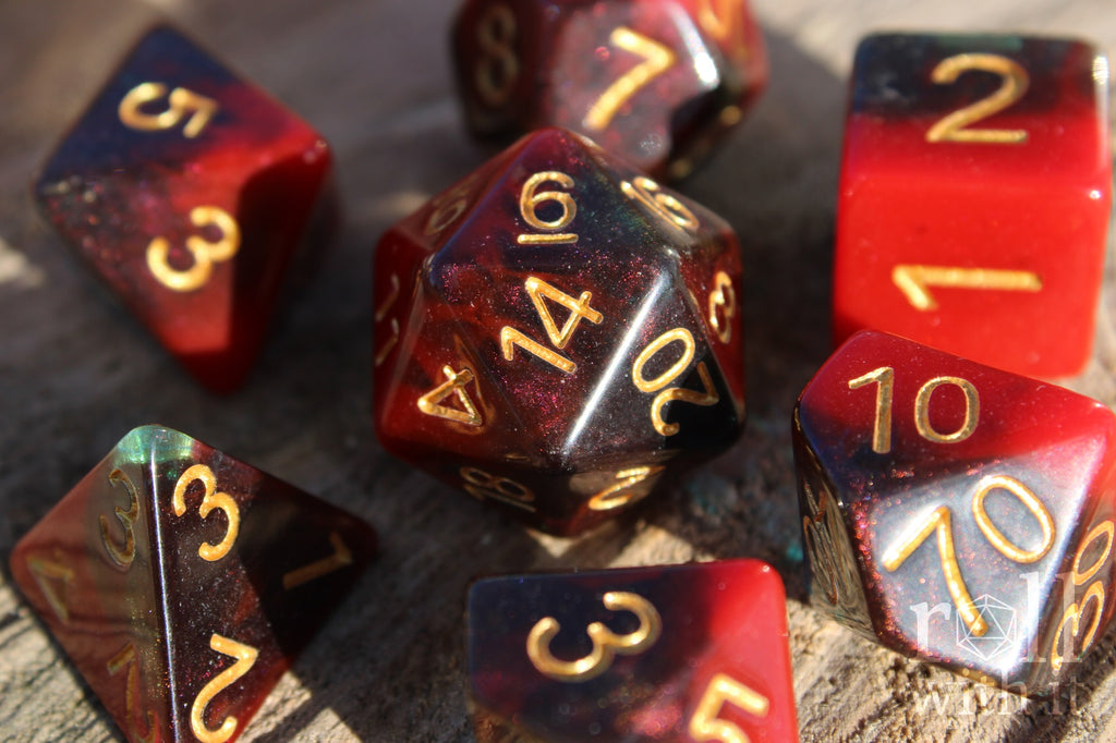 Set of colourful red and deep blue glittery polyhedral dice with gold numbers on a wooden surface