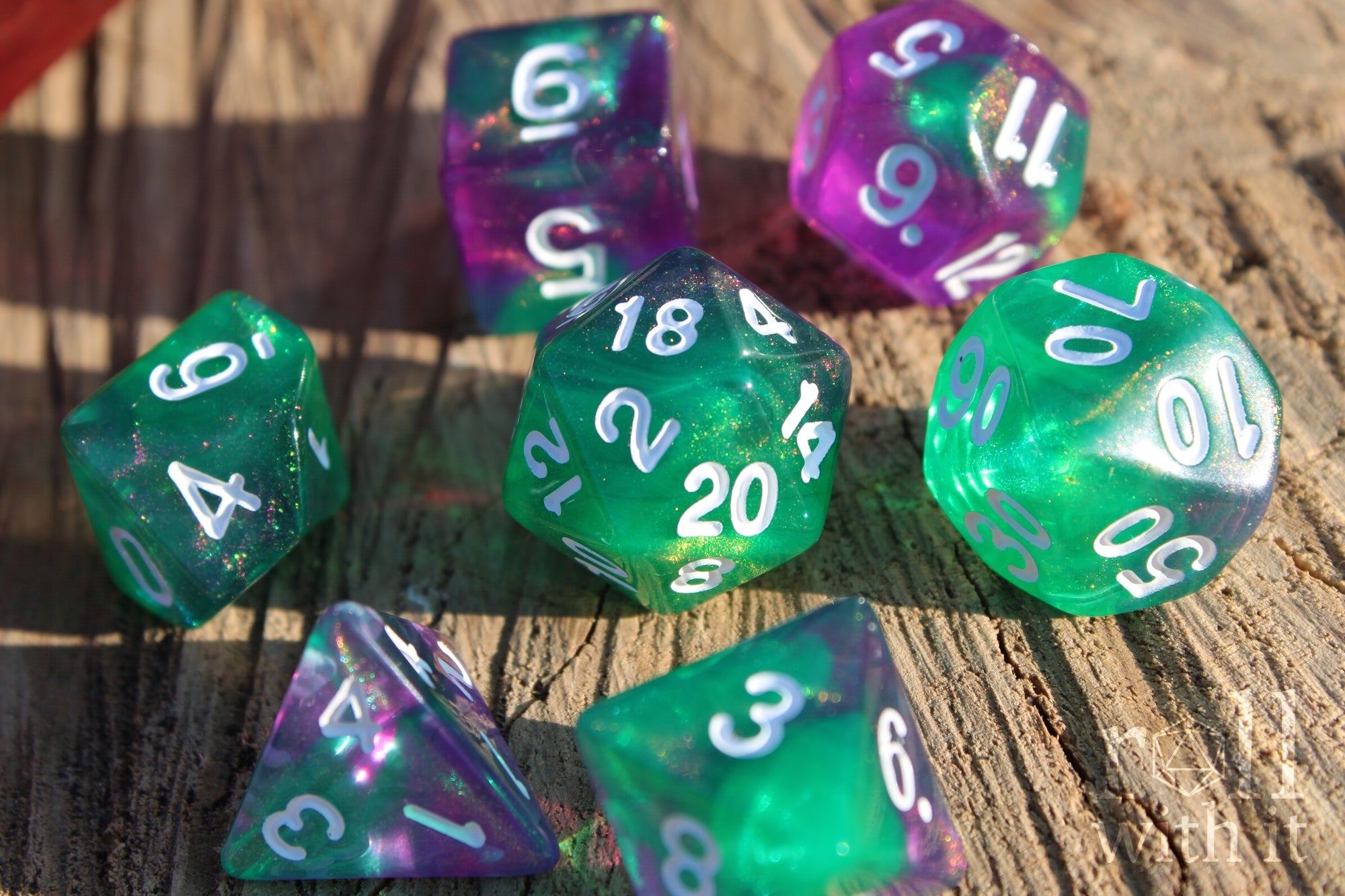 Set of colorful and glittery green and purple polyhedral dice on a wooden surface