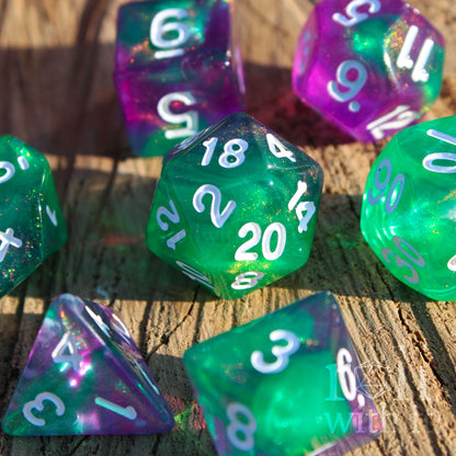 Set of colorful and glittery green and purple polyhedral dice on a wooden surface