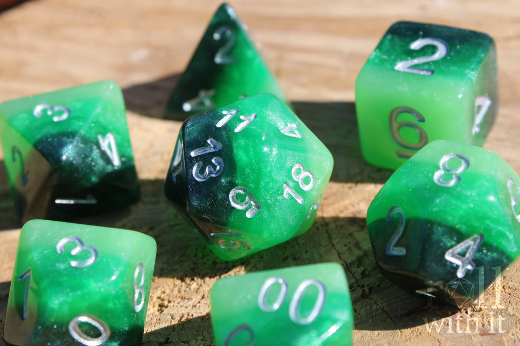 Green and black glittery polyhedral roleplaying dice set on a wooden surface