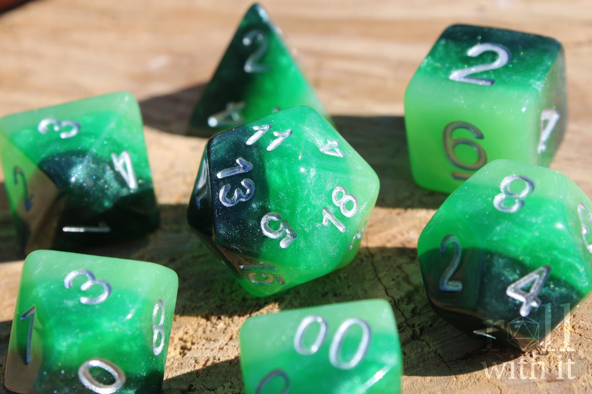 Green and black glittery polyhedral roleplaying dice set on a wooden surface