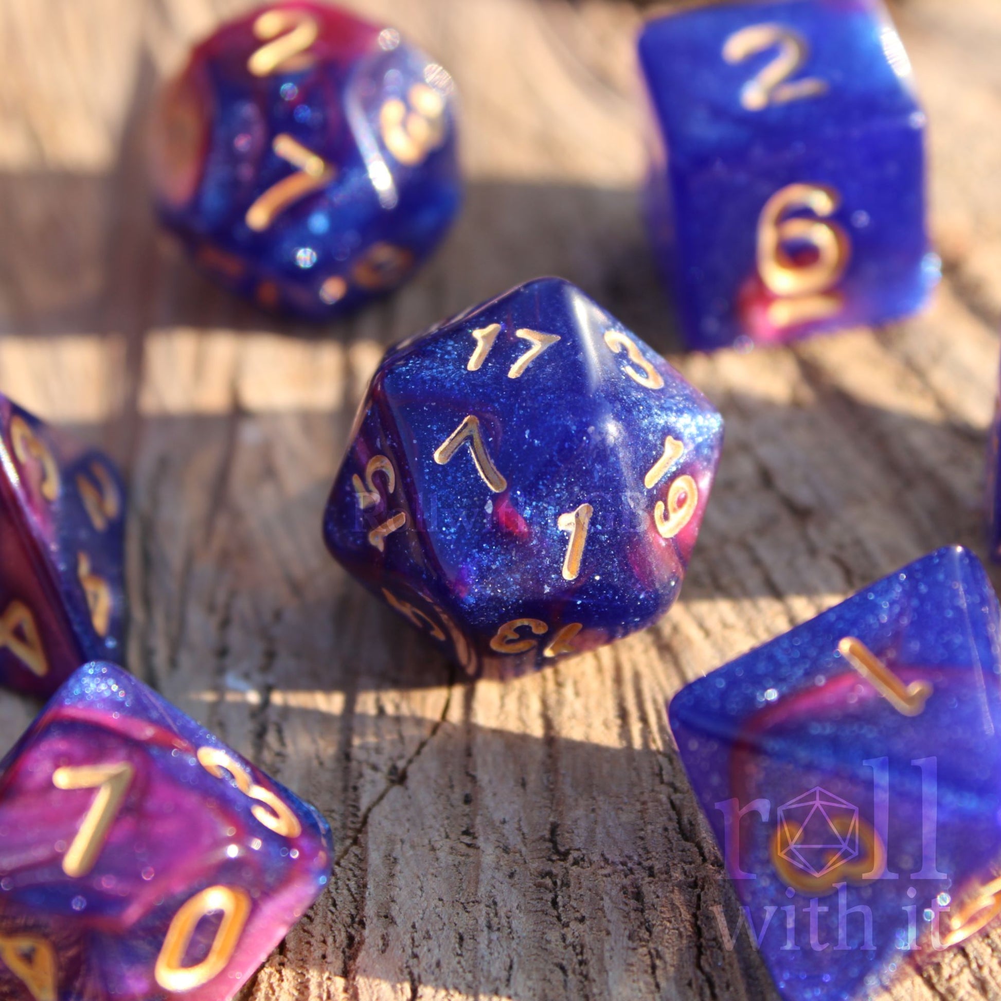 Set of purple and blue polyhedral dice with gold numbers on a wooden surface