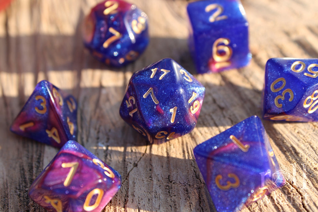 Set of purple and blue polyhedral dice with gold numbers on a wooden surface