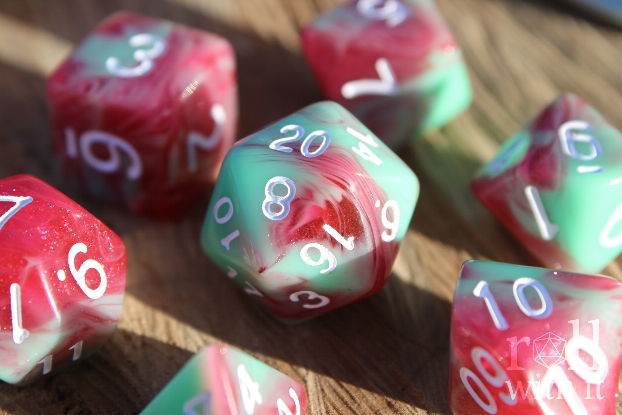 Set of glittery red and pastel green polyhedral roleplaying dice on a wooden surface