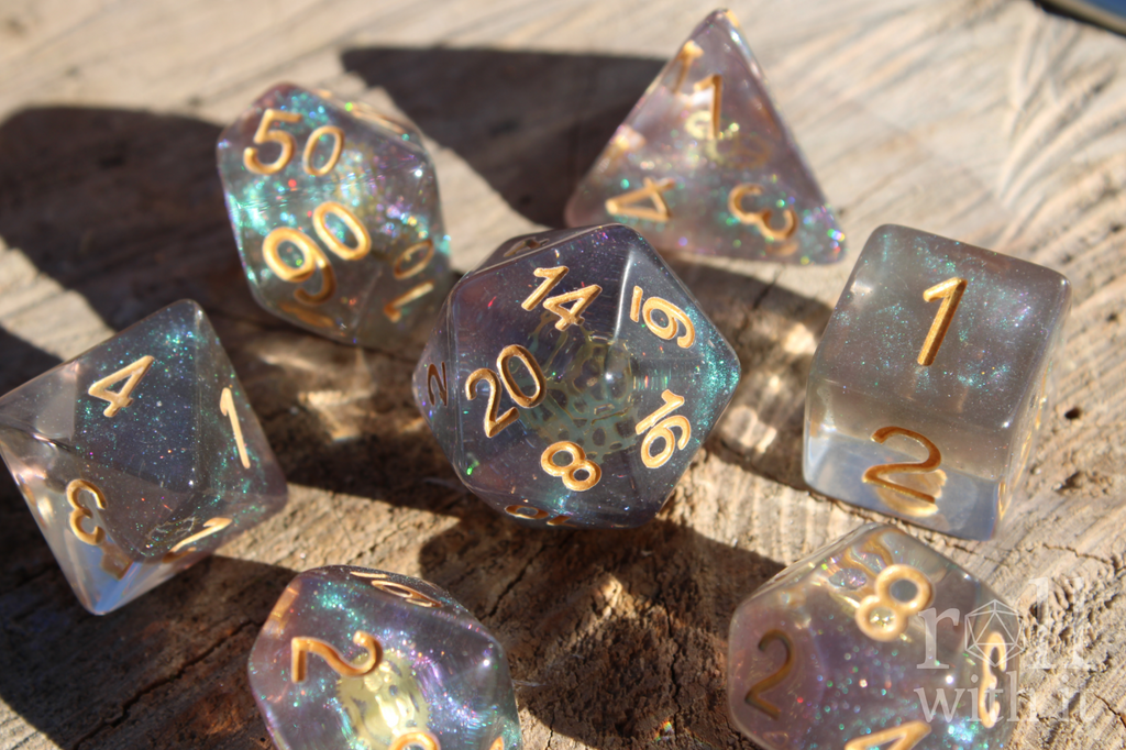 Set of iridescent glittery and starry roleplaying dice with gold numbers and golden cogs inside on a wooden surface