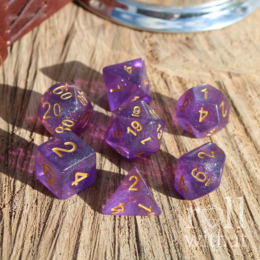 Purple polyhedral dice set with gold numbers on a wooden surface