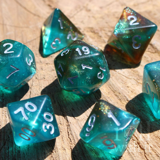 Set of 7 turquoise blue and copper glittery polyhedral roleplaying D&D dice with white numbers on a wooden surface