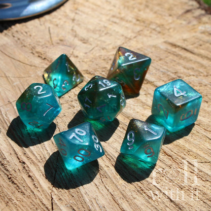 Set of 7 blue teal glow in the dark polyhedral dice on a wooden surface