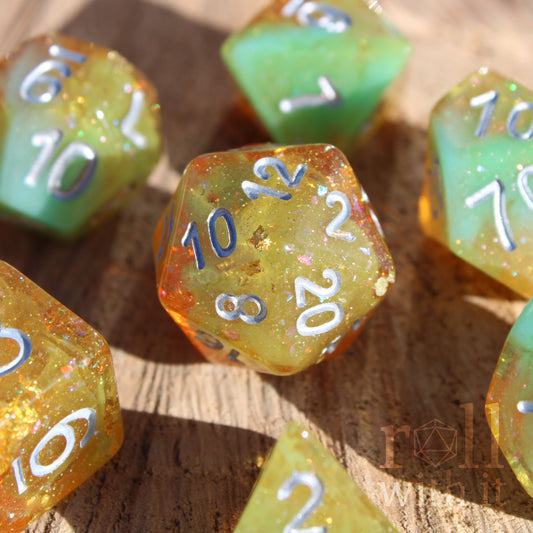 Set of colourful and glittery golden and teal polyhedral roleplaying DND dice with silver numbers on a wooden surface