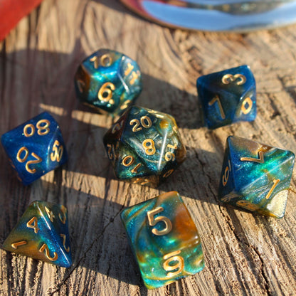 Set of glittery mixed blue, green, and gold polyhedral roleplaying dice on a wooden surface
