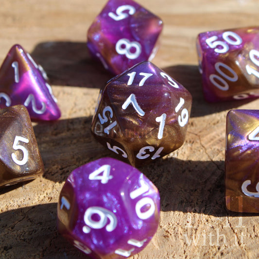 Set of 7 purple and gold polyhedral glitter fantasy roleplaying dice with white numbers on a wooden surface