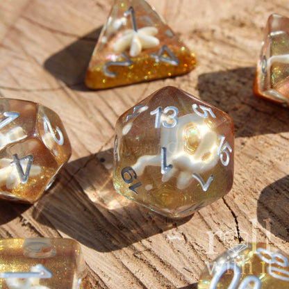 Set of golden glittery sandy clear polyhedral dice with a seashell inside on a wooden surface