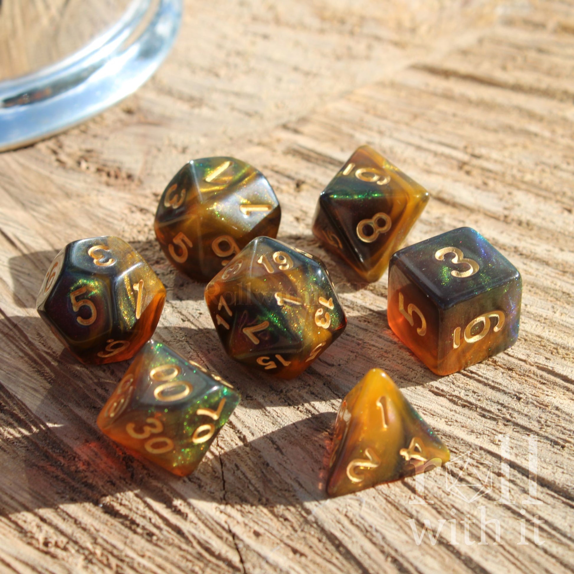 Set of gold brown green glitter polyhedral dice with gold numbers on a wooden surface