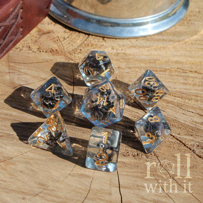 Top view of 7 TTRPG pathfinder compatible dice made from blue aqua coloured resin with mini ships inside on a wooden surface