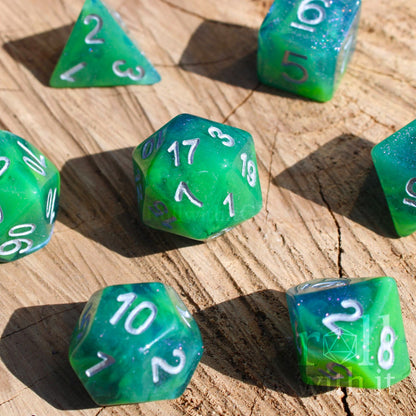 Set of green and blue glittery polyhedral DND dice with silver numbers on a wooden surface