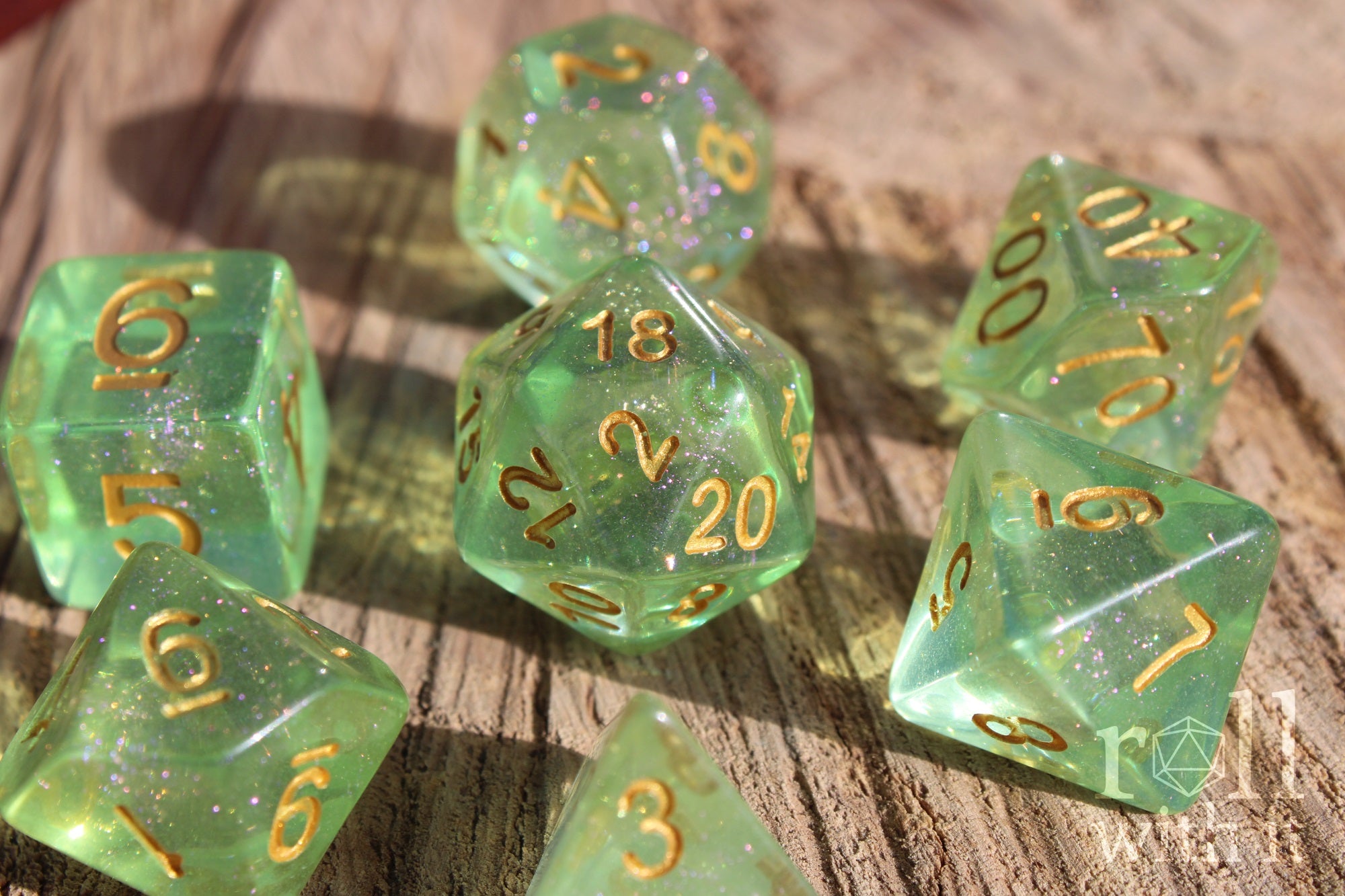 Set of green shimmering polyhedral roleplaying dice with gold numbers on a wooden surface