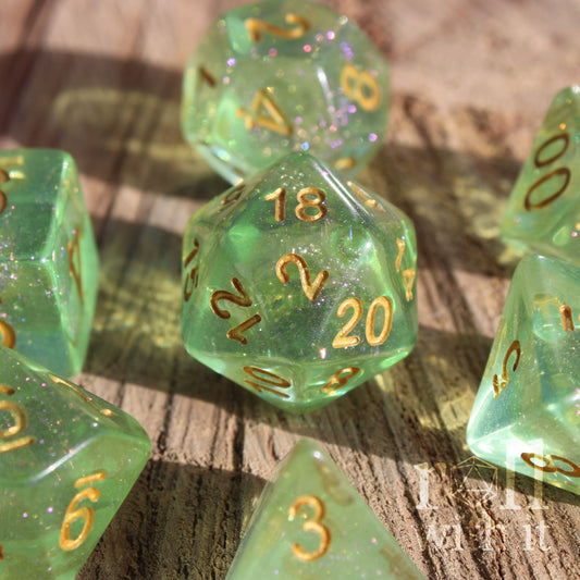 Set of green shimmering polyhedral roleplaying dice with gold numbers on a wooden surface