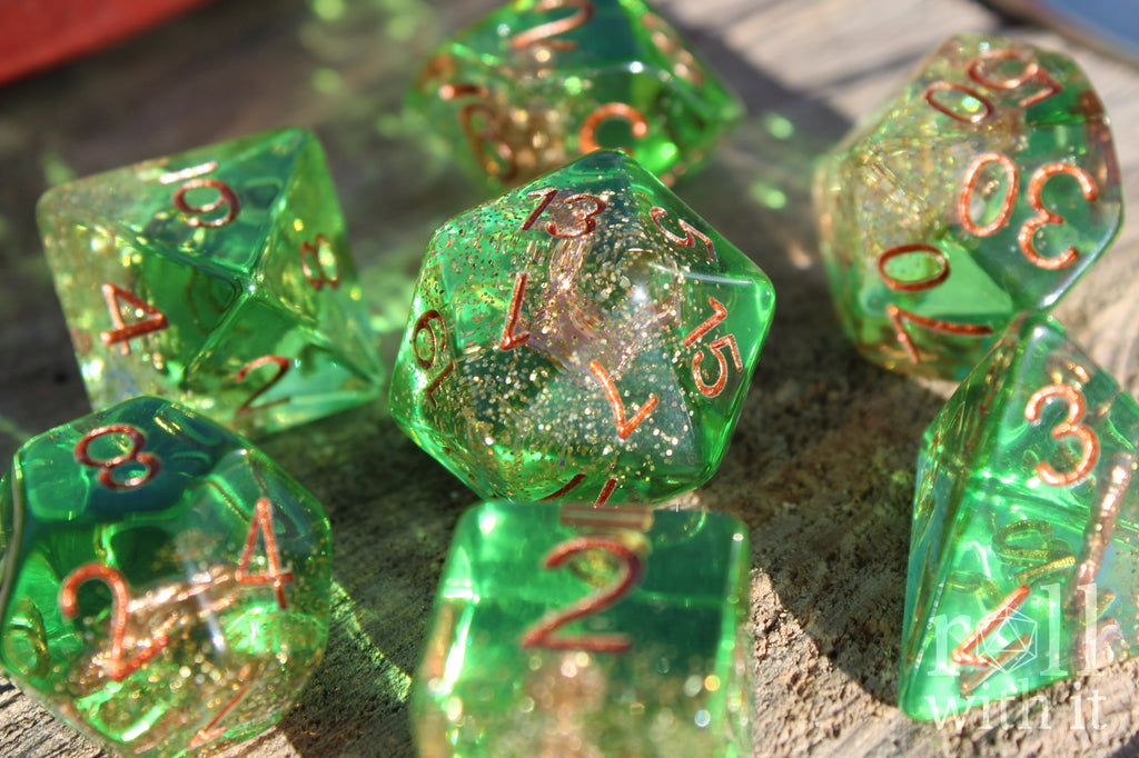 Set of green golden glittery dice with an anchor inside polyhedral dice with copper numbers on a wooden surface