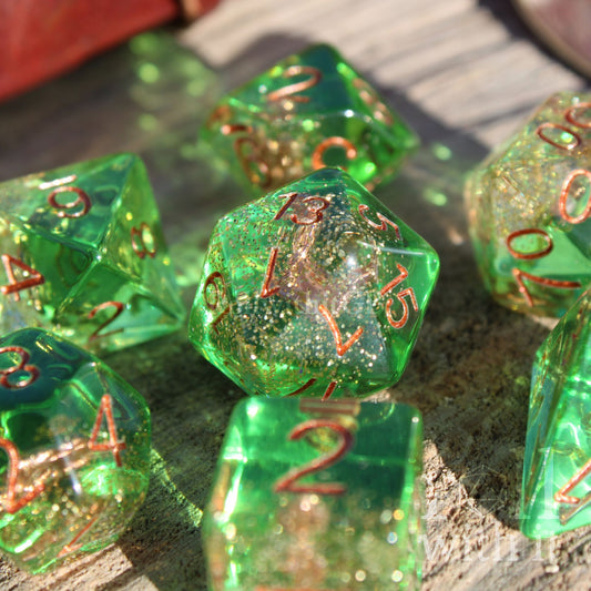 Set of green golden glittery dice with an anchor inside polyhedral dice with copper numbers on a wooden surface