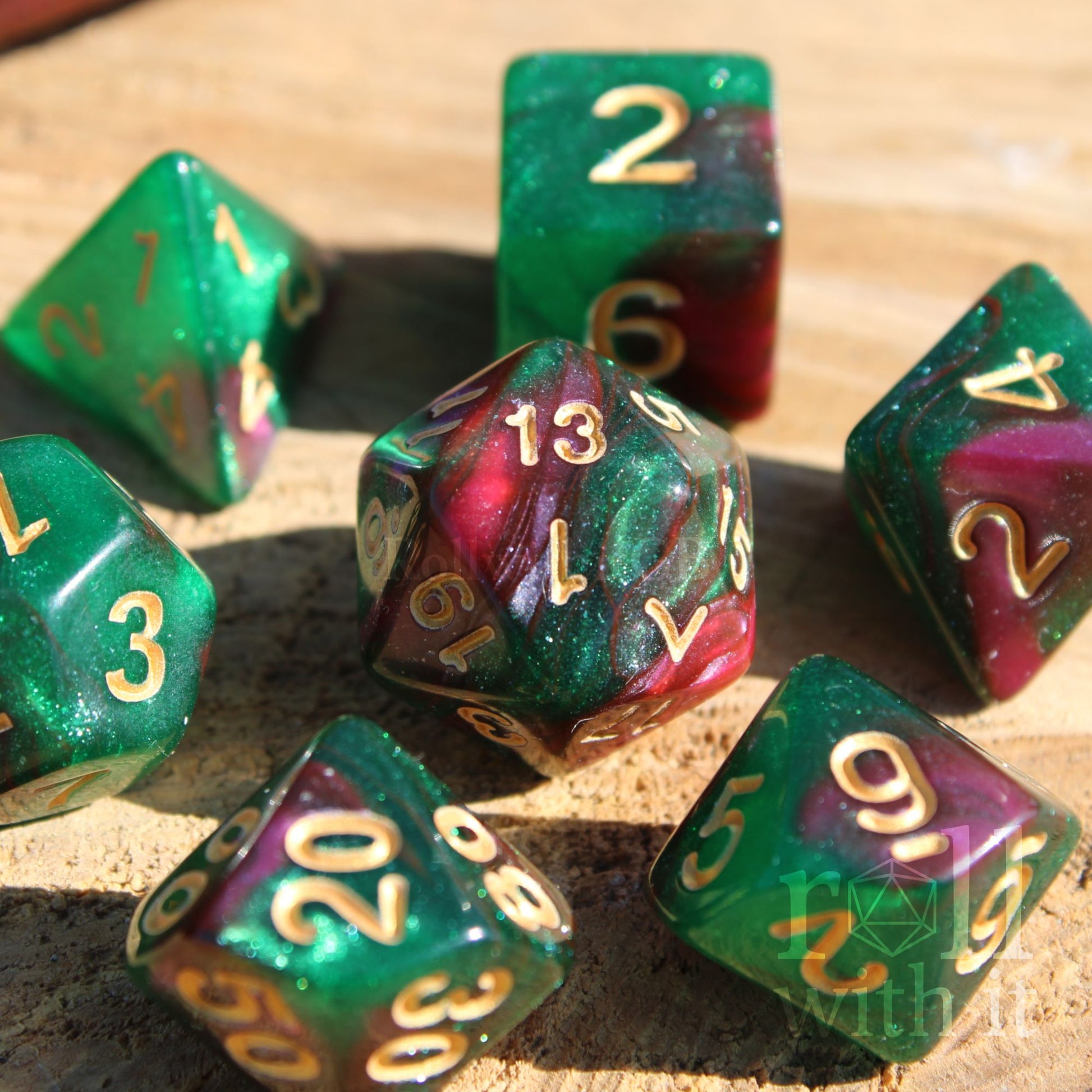 Set of glittery and shimmering green and purple polyhedral dice with gold numbers on a wooden surface