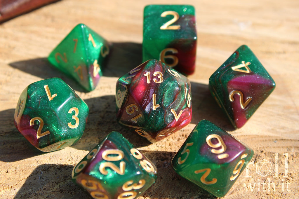 Set of glittery and shimmering green and purple polyhedral dice with gold numbers on a wooden surface