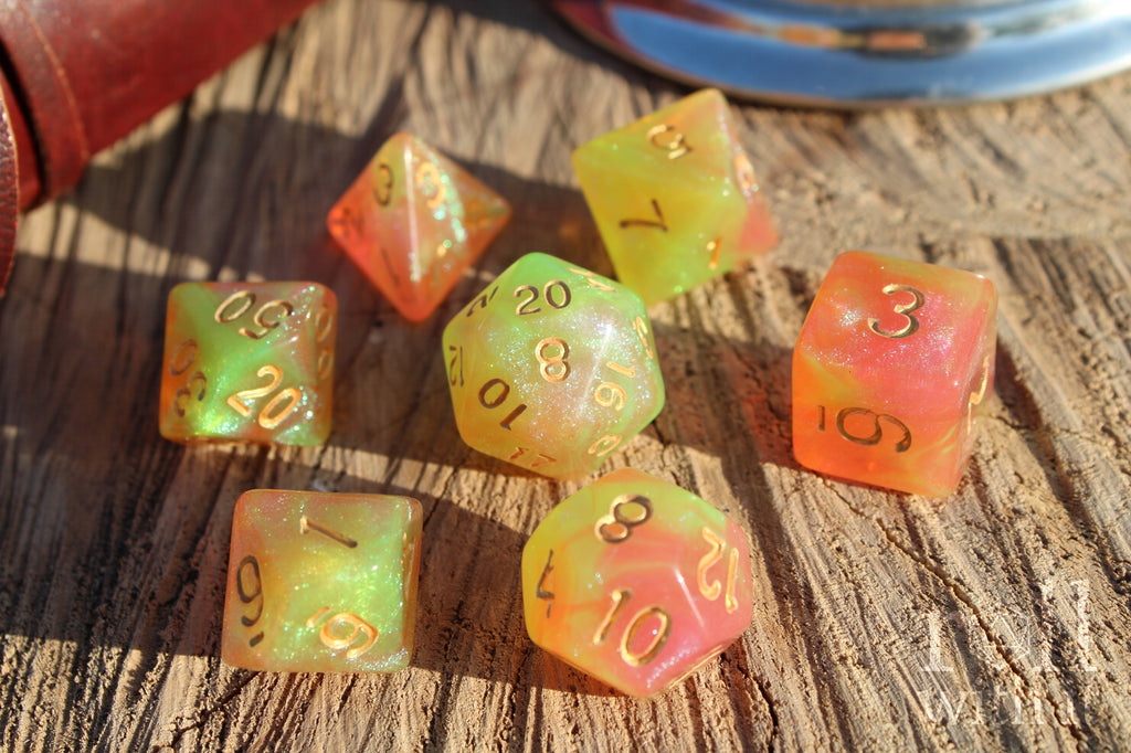 Set of colourful glittery light green and peachy pink polyhedral dice on a wooden surface