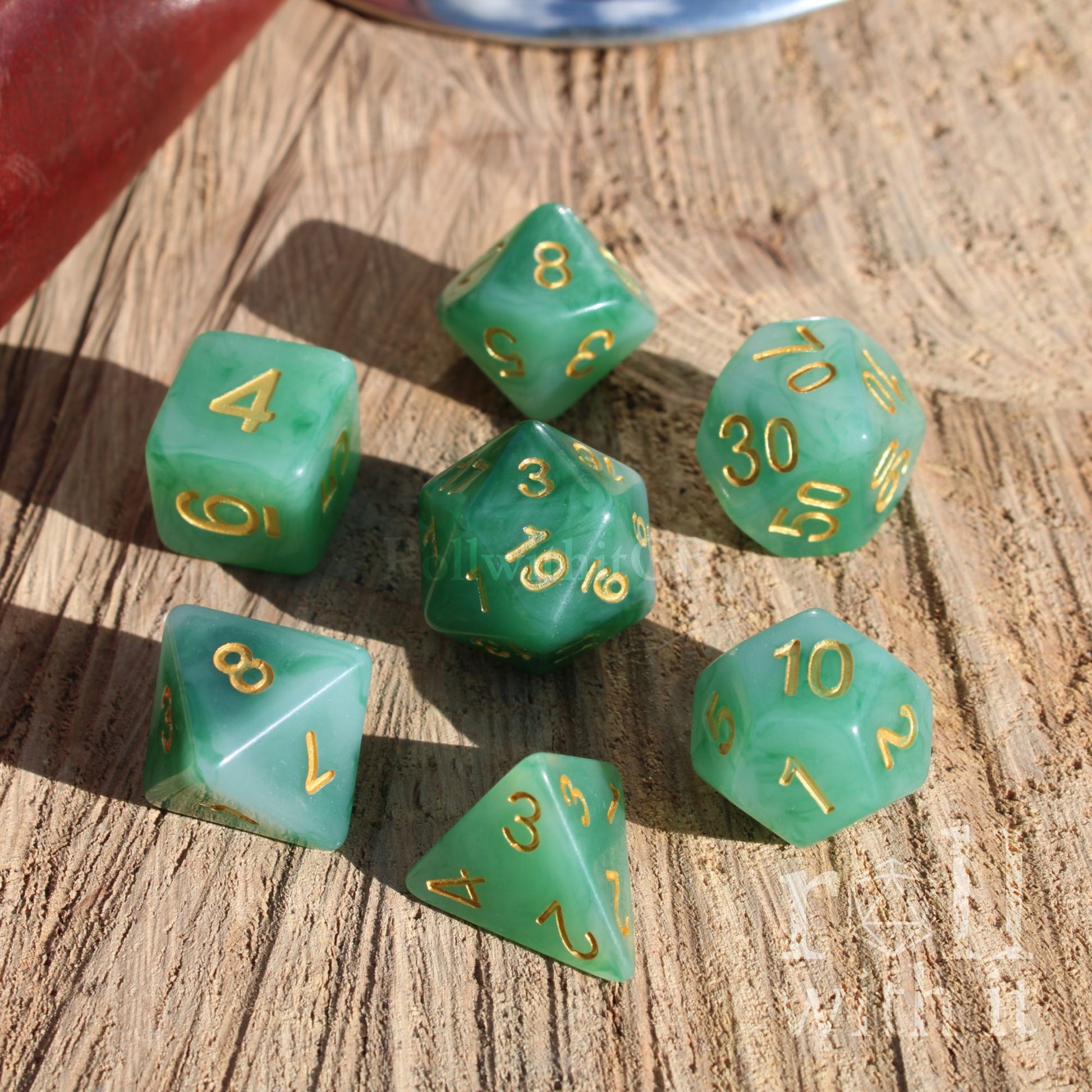 Set of milky green tabletop polyhedral dice with gold numbers on a wooden surface