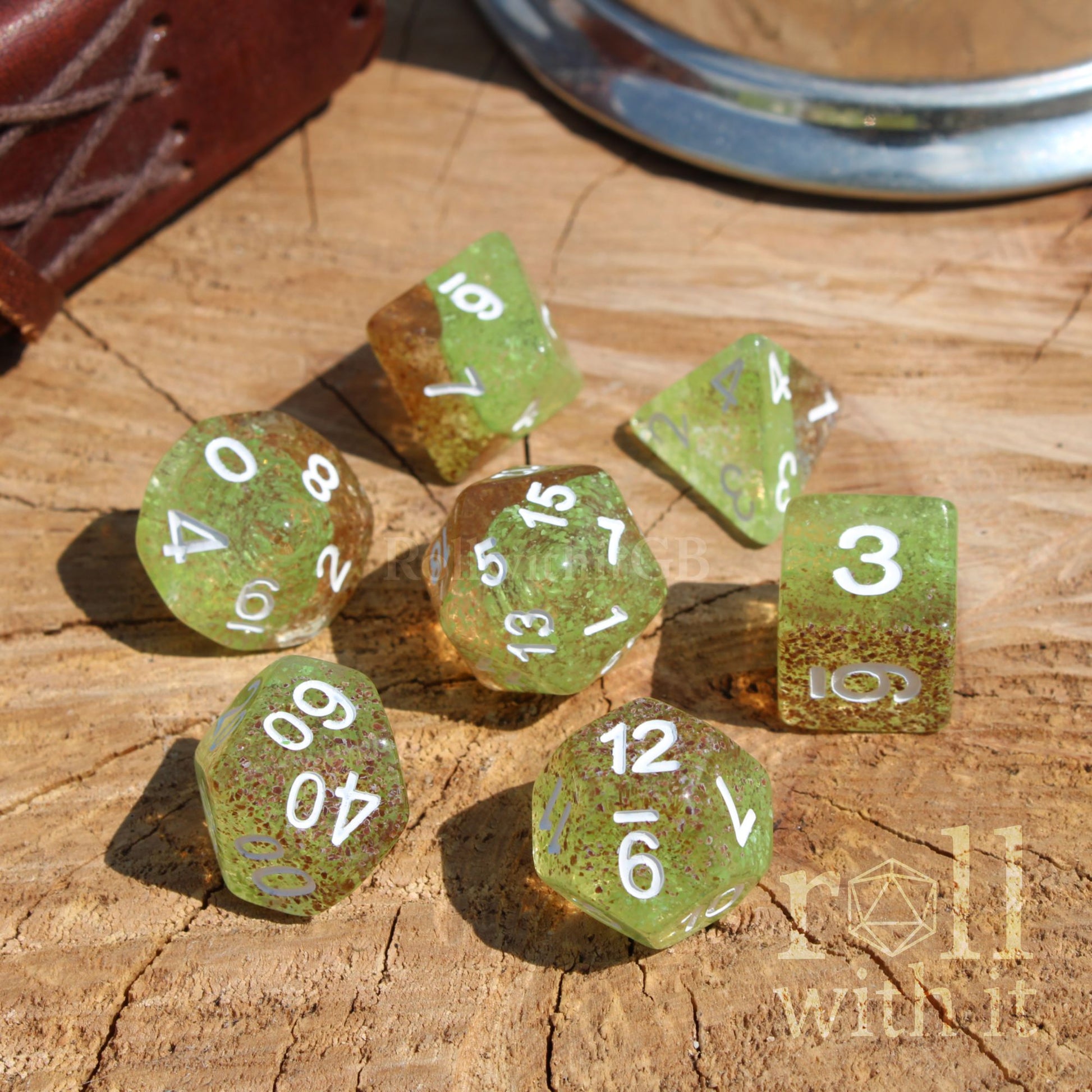 Set of green orange polyhedral dice on a wooden surface with white lettering
