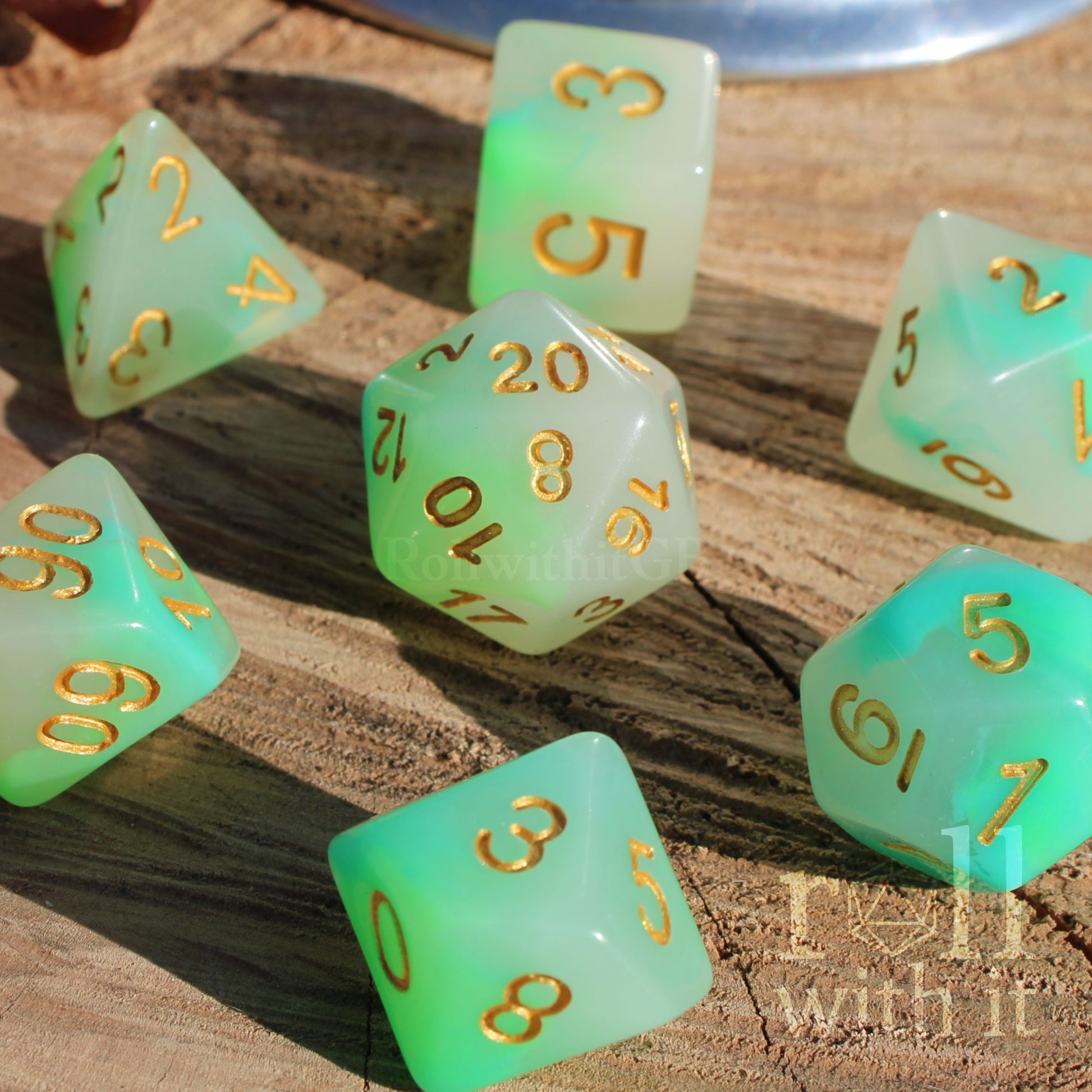 Set of turquoise and green polyhedral DND dice with gold numbers on a wooden surface